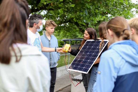 Nahaufnahme, dass einen Solarmonteur mit einer Schülerin bei der Montage eines Moduls zeigt.